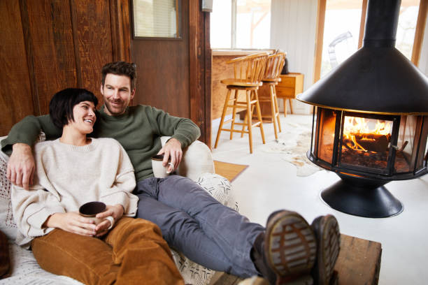 istock Laughing couple warming up by a fireplace with cups of tea 1225576139