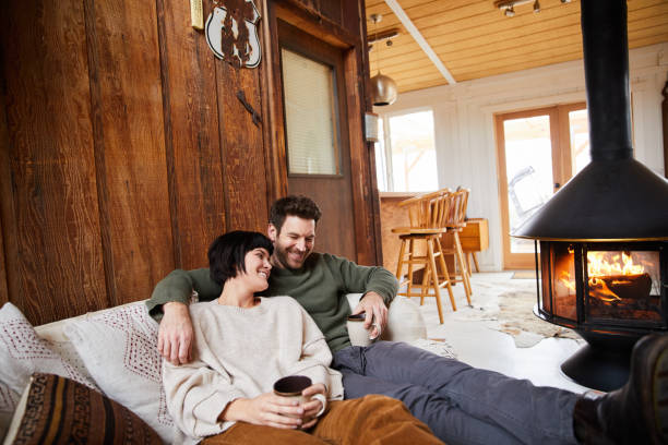 istock Laughing couple drinking tea and warming up by a their cabin fireplace 1225576350