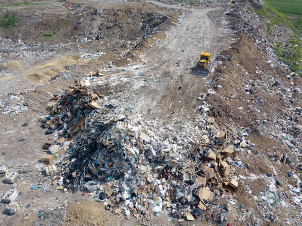 istock yellow tractor on dump in field. garbage collection, environmental disaster. 1225576725