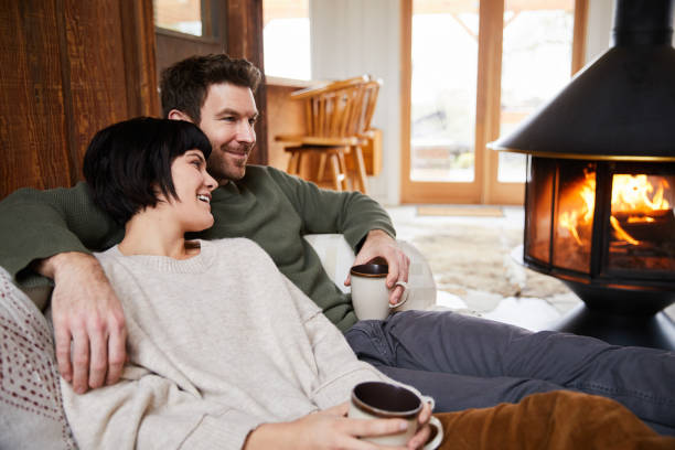 istock Smiling couple talking over tea while warming up by their cabin fireplace 1225576783