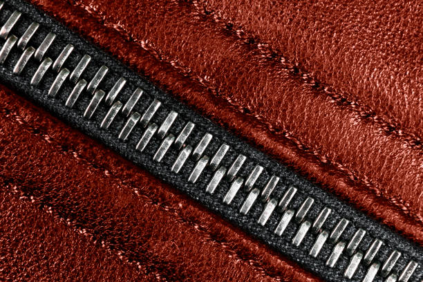 Macro shot of zipper on red leather texture background with stitching. Horizontal background from a close-up of red leather material