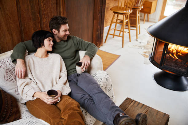 istock Smiling couple drinking tea and warming up by a their cabin fireplace 1225577810