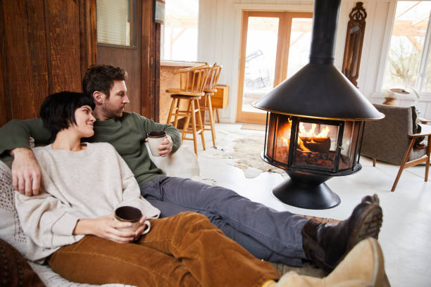 istock Smiling couple warming up by a fireplace with cups of tea 1225577979