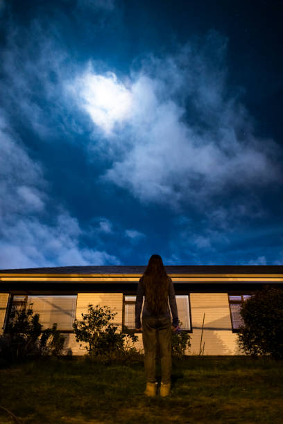 istock Woman looking at beautiful night sky lit by full moon 1225582737