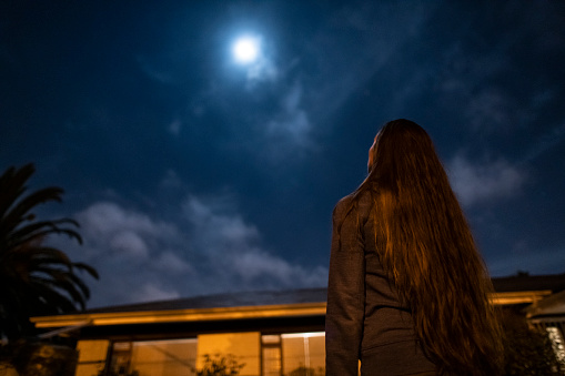 Low angle woman looking up to the full moon