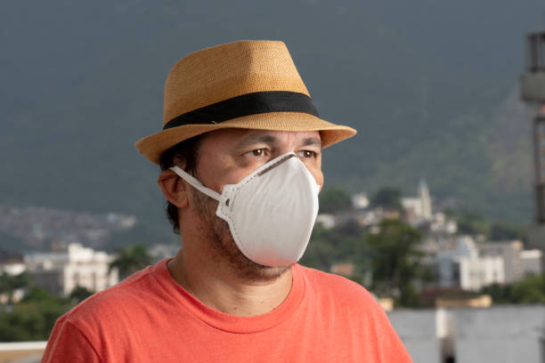 man wearing N-95 mask to protect himself from covid-19 on the balcony of his residence