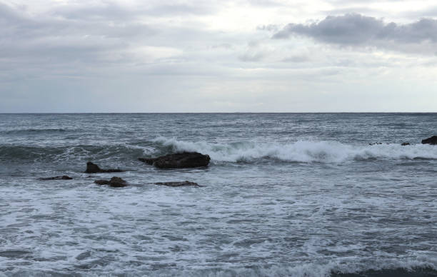 오후에 황혼에 미친 바다. 물은 바위 위로 흐르고 수백만 방울로 부서집니다. 작은 일반 간헐천이 형성됩니다. 하늘은 모든 색상으로 재생됩니다. 파포스 비치, 키프로스 - cyprus paphos storm sea 뉴스 사진 이미지