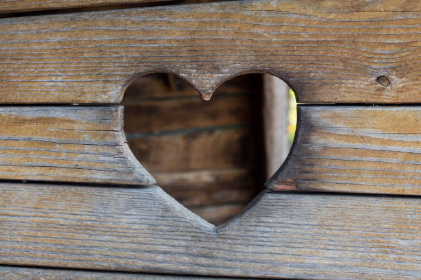 Looking through a carved heart in a wooden wall to city Garmisch-Partenkirchen in Bavaria, Germany, at cold winter night