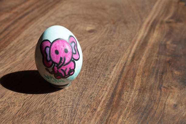 istock Colorful painted Easter egg with pink elephant in wooden background 1225585108