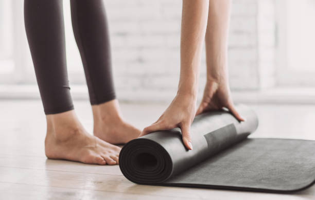istock Woman rolling up exercise mat and preparing doing yoga 1225585559
