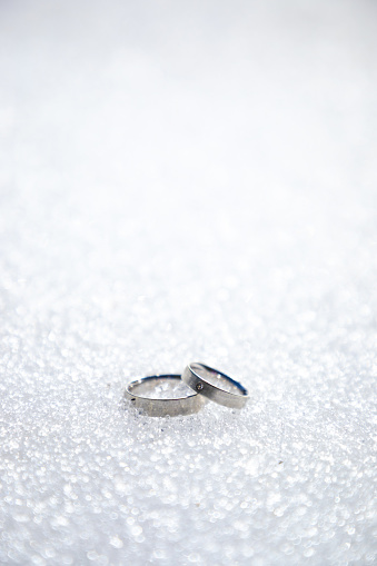 Silver or white gold engagement rings on snow or sparkling white background with copy space