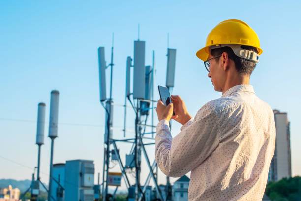 engineer holding mobile phone testing the communications tower - high frequencies imagens e fotografias de stock