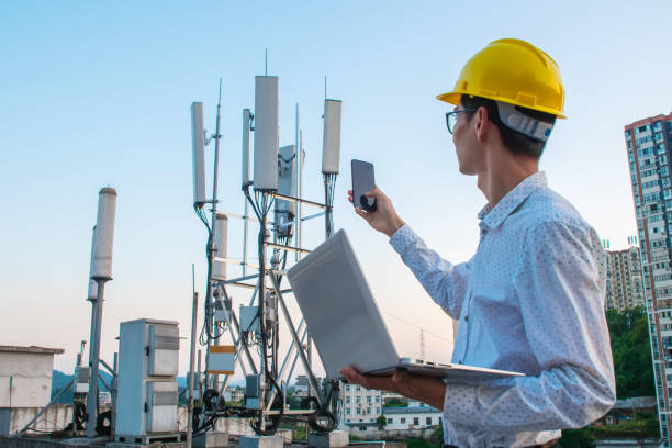 ラップトップと電話で作業しているエンジニア、通信塔のチェック - tower communications tower mobile phone antenna ストックフォトと画像