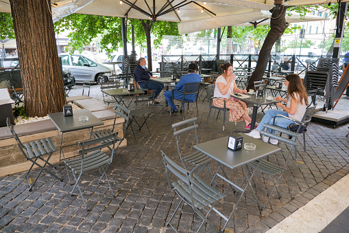 Rome, Italy, May 18 -- Some people sitting outside a cafeteria in the center of Rome maintain social distancing after the end of the restrictions imposed by the lockdown for the Covid-19 crisis. The tables were spaced mainly after new indications from the Italian authorities.