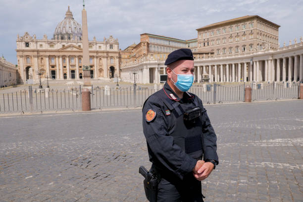 An Italian policeman in the deserted square of St. Peter's Basilica during the first lockdown for the Covid-19 Vatican, Italy, May 18 -- An Italian officer of Carabinieri checks the square of the basilica of St. Peter's, still empty despite the end of the restrictions imposed by the lockdown for the Covid-19 crisis. church of san pietro photos stock pictures, royalty-free photos & images