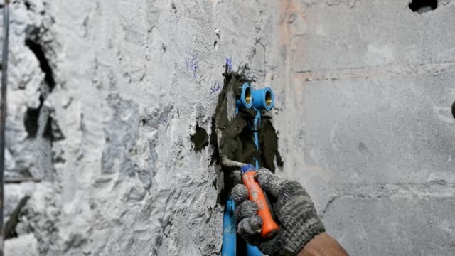 Plasterer plastering on brick wall in bathroom