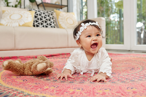Little Asian baby girl enjoying crawling on the floor in spacious playroom