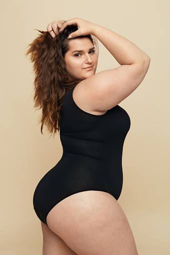 Plus Size Model Fat Woman In Black Bodysuit Portrait Brunette Touching Hair  And Looking At Camera Body Positive Concept On Beige Background Stock Photo  - Download Image Now - iStock
