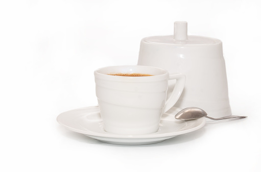 White cup of coffee with a sugar bowl on a white background stand on a saucer.