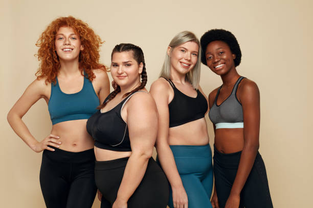 Different Race. Diversity Figure And Size Women Portrait. Smiling Multiethnic Female In Sportswear Posing On Beige Background. Body Positive As Lifestyle. Different Race. Diversity Figure And Size Women Portrait. Smiling Multiethnic Female In Sportswear Posing On Beige Background. Body Positive As Lifestyle. sports clothing stock pictures, royalty-free photos & images