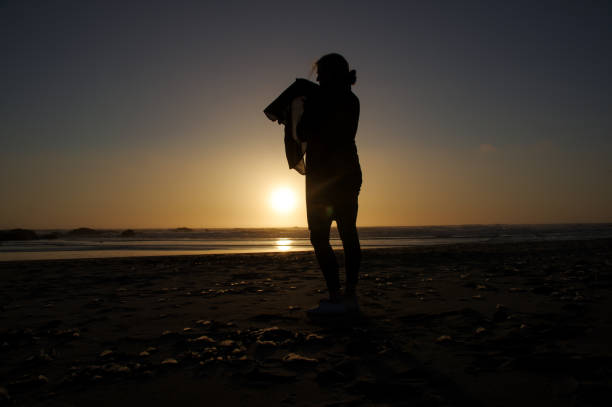 istock Woman in silhouette on the beach 1225597086
