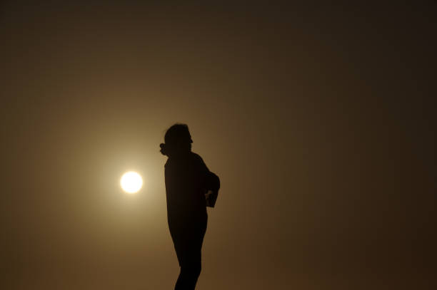 istock Woman in silhouette on the beach 1225597115