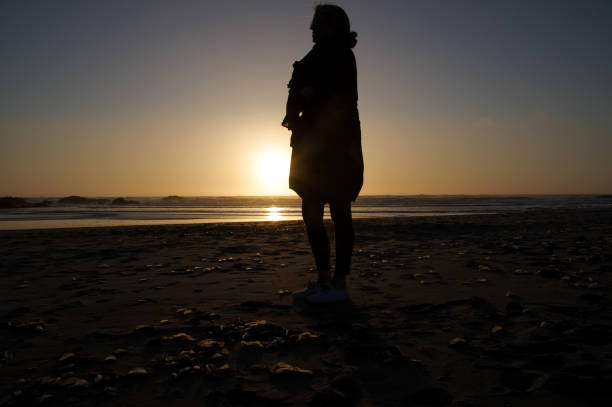 istock Woman in silhouette on the beach 1225597708