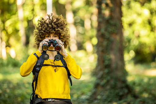 Female explorer looking through binocular in the mountains