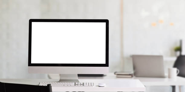 istock Computer monitor with white blank screen putting on white working desk and surrounded by mouse and keyboard over comfortable office. 1225598492