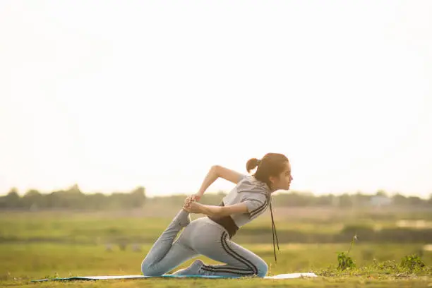 Portrait of a Young Woman performing Yoga outside in sunny bright light.