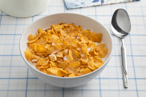 Bowl with traditional cornflakes and milk close up