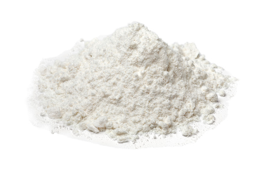 Heap of white wheat flour close up  isolated on white background