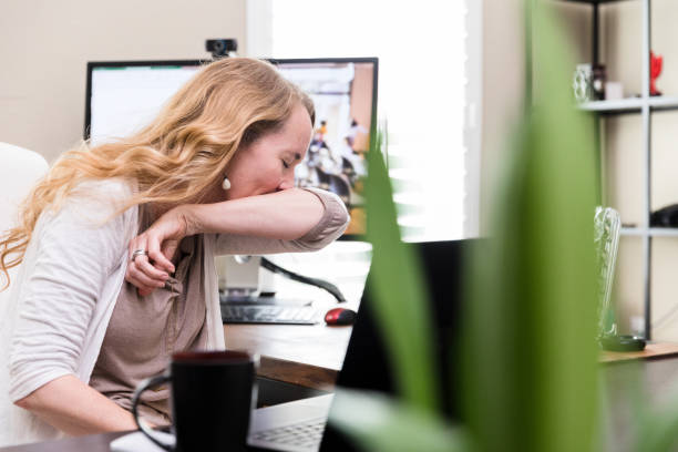 istock Businesswoman sneezes into elbow while working from home 1225603765