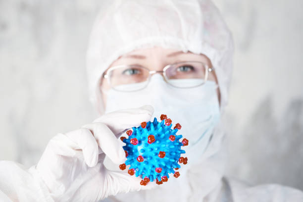 istock woman in protective suit holds coronovirus model 1225610070