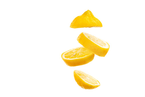 Sliced lemon floating on white background. Fruit slice falling on bright backdrop.