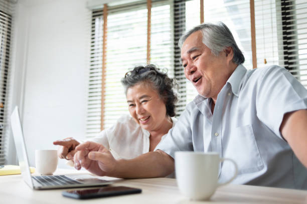 couples asiatiques de soins de sécurité d’une personne qui font l’appel vidéo et parlent avec la famille sur l’ordinateur portable. happy smiling japonais vieil homme et femme profiter avec la technologie d’internet sur la table à la maison. st - senior couple isolated couple senior adult photos et images de collection