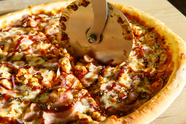 istock Chef baker in uniform cutting freshly pizza slices 1225611921