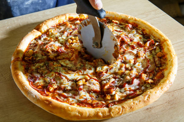 istock Chef baker in uniform cutting freshly pizza slices 1225611931