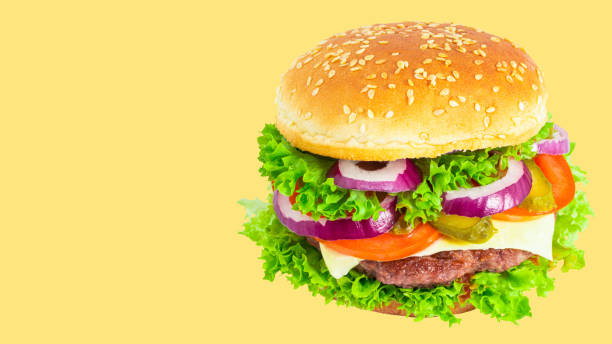 istock fresh tasty burger isolated on yellow background.  Copy space 1225613960