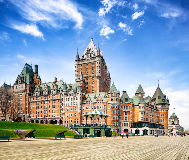 Quebec City Terrasse Dufferin et Chateau Frontenac Hotel on a sunny Springtime day. Several people are walking on the terrasse below the emblematic building.
