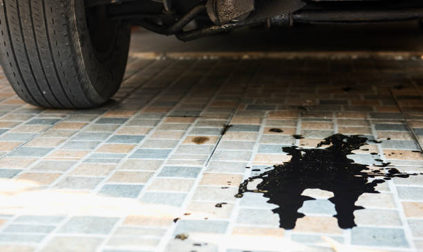 l'olio perde o scende dal motore dell'auto sul parcheggio. servizio di ispezione e manutenzione auto - oil slick foto e immagini stock
