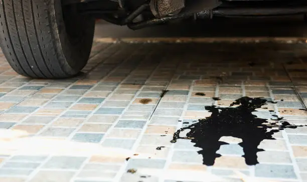 Oil leaks or drops from the car's engine on the parking lot. Car inspection and maintenance service