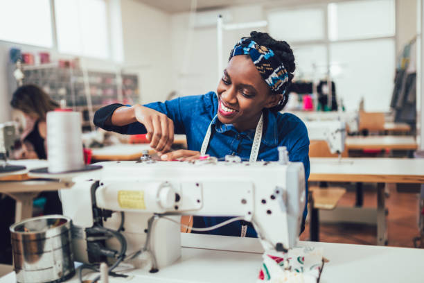 giovane operaio tessile africano che cuce sulla linea di produzione. donna sarta che lavora con la macchina da cucire - sewing textile garment industry foto e immagini stock