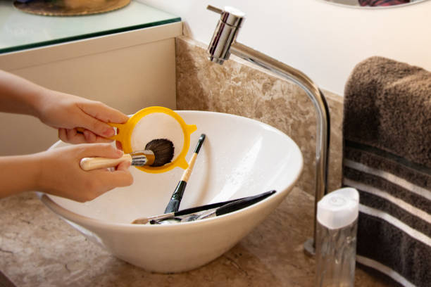 istock washing makeup brush in bathroom sink 1225622420