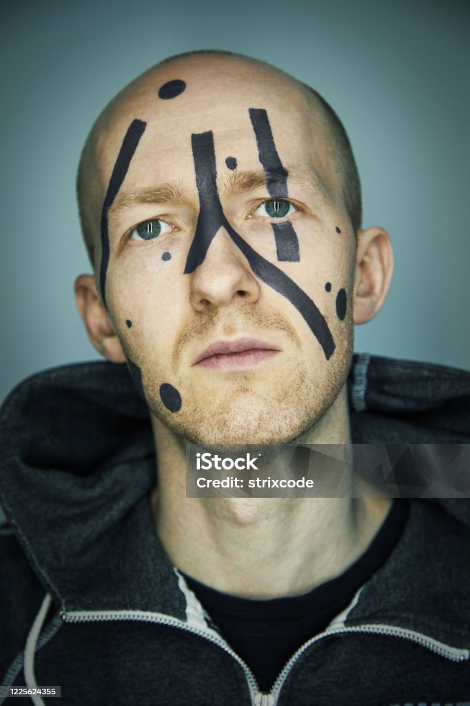 Close up portrait of man hiding his face from camera recognition with special camouflage makeup. Digital privacy in big city concept image. Human Face Stock Photo