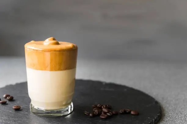 Photo of Dalgona coffee whipped cream mousse against grey background, also dubbed as quarantine drink