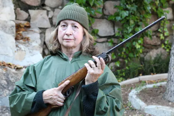 Mature huntress holding a rifle.