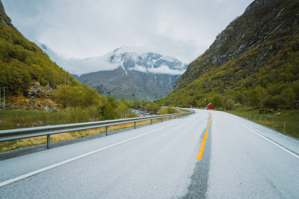 istock Asphalt road leading between high snow-covered mountains in Norway 1225627816