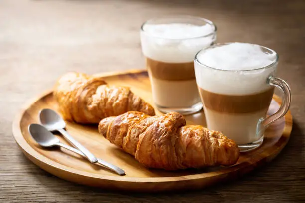 glasses of latte macchiato coffee and croissants on a wooden table