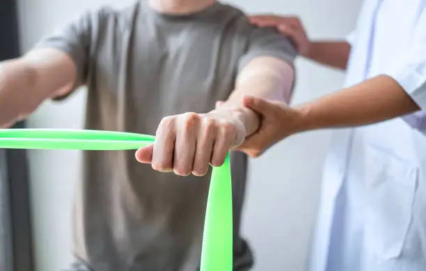 Photo of Female Physiotherapist working examining treating injured arm of athlete male patient, stretching and exercise, Doing the Rehabilitation therapy pain in clinic